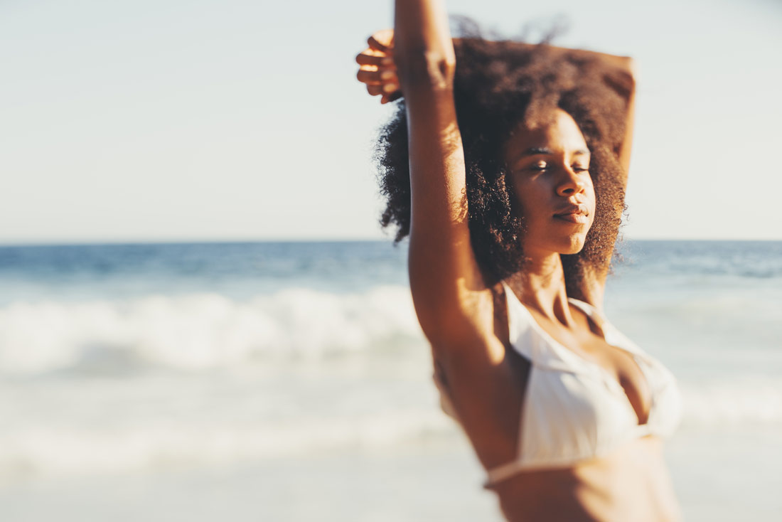 mulher tomando sol na praia absorvendo vitamina d